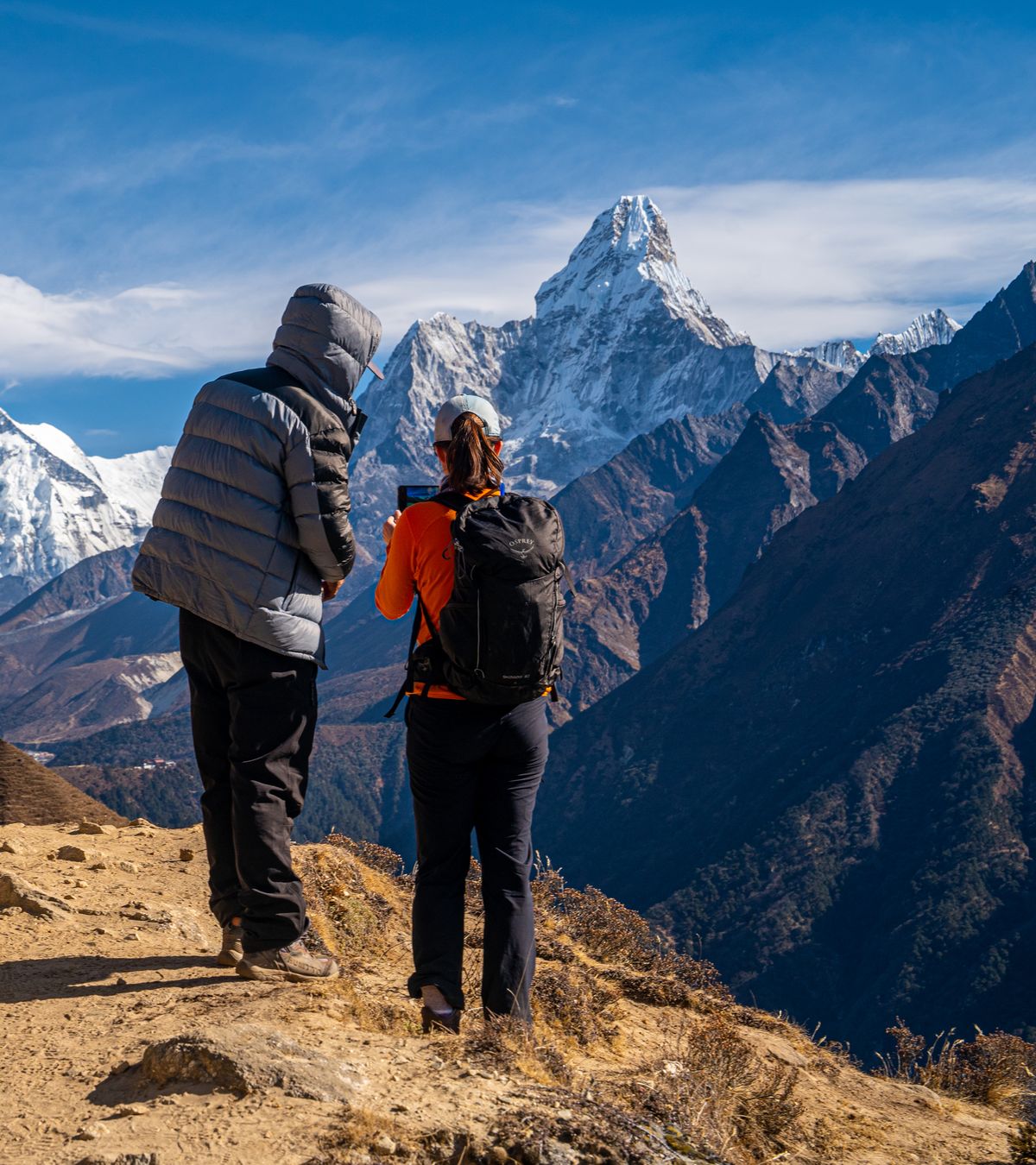 Two trekkers pausing on a Khumbu trail to take in Ama Dablam
